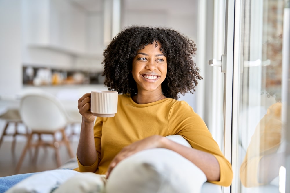 african woman find happiness in taking tea while sitting at couch